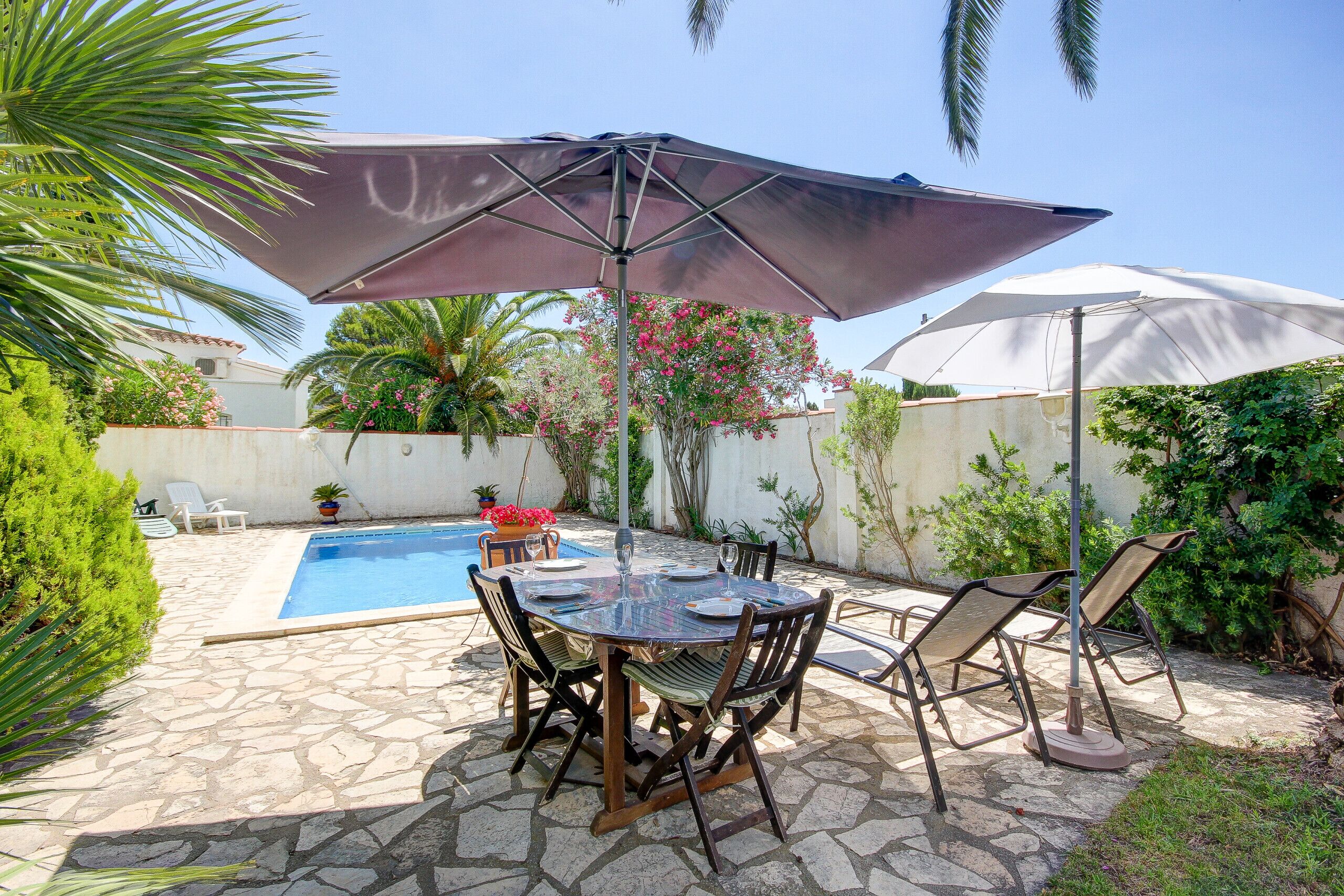 A patio with a pool, stone flooring, and outdoor furniture.