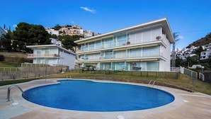 Un hôtel moderne doté d’une grande piscine, de nombreux balcons et offrant une vue sur les collines environnantes.
