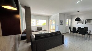 A modern living room with a sofa, a dining table with chairs, and a TV. - Agi Drugstore AD Apartamento for rent in Roses Girona. (Rosas / Roses)