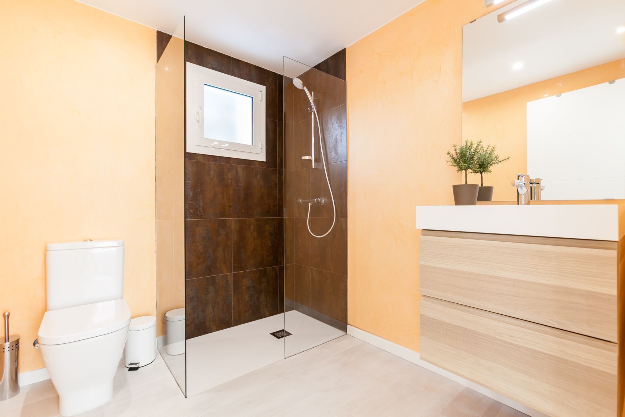Une salle de bain moderne équipée d’une douche, de toilettes et d’un meuble-lavabo.