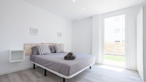 A modern bedroom with a bed, a bedside table, and a view of the outdoors. - Apartment with private garden and communal jacuzzi, next to the beach and the center (Roses)