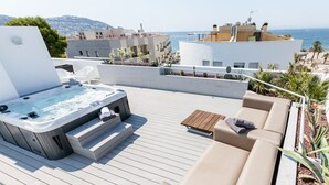 A rooftop deck with a hot tub, beige outdoor furniture, and a view of the sea and buildings. - Apartment with private garden and communal jacuzzi, next to the beach and the center (Roses)