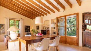 A spacious dining area with a wooden table, white chairs, and a hanging lamp. - Private retreat with pool near the sea (Son Servera)