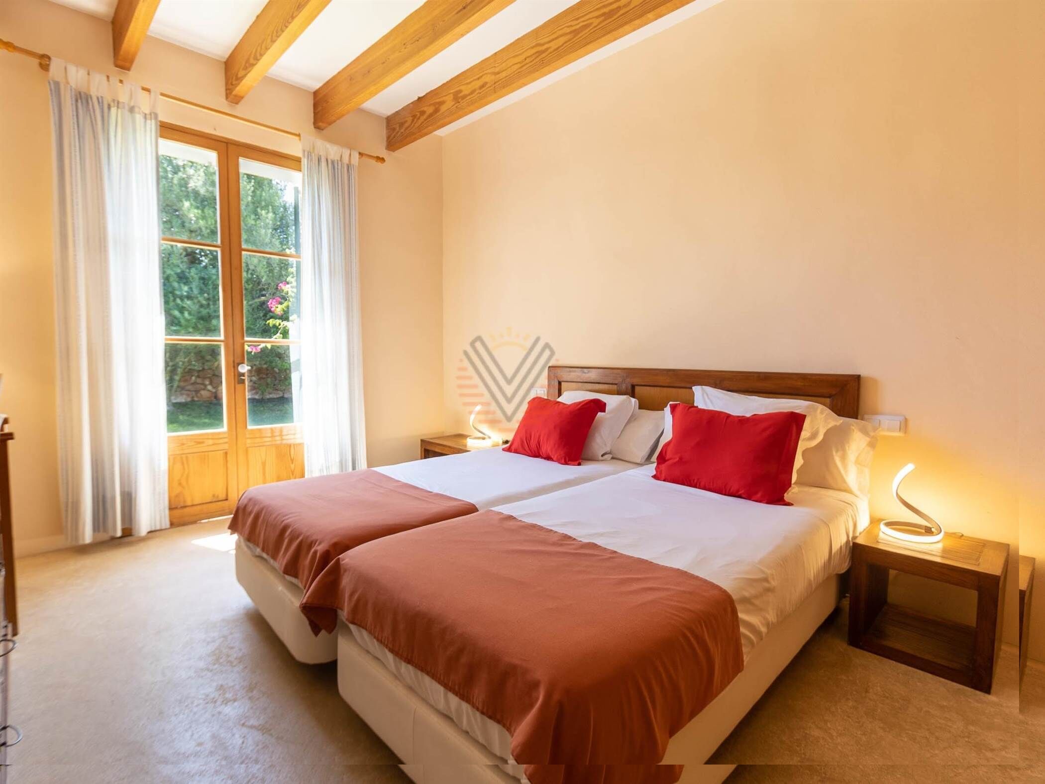 Una cama doble con ropa de cama roja y blanca, un cabecero de madera y una mesita de noche con una lámpara.