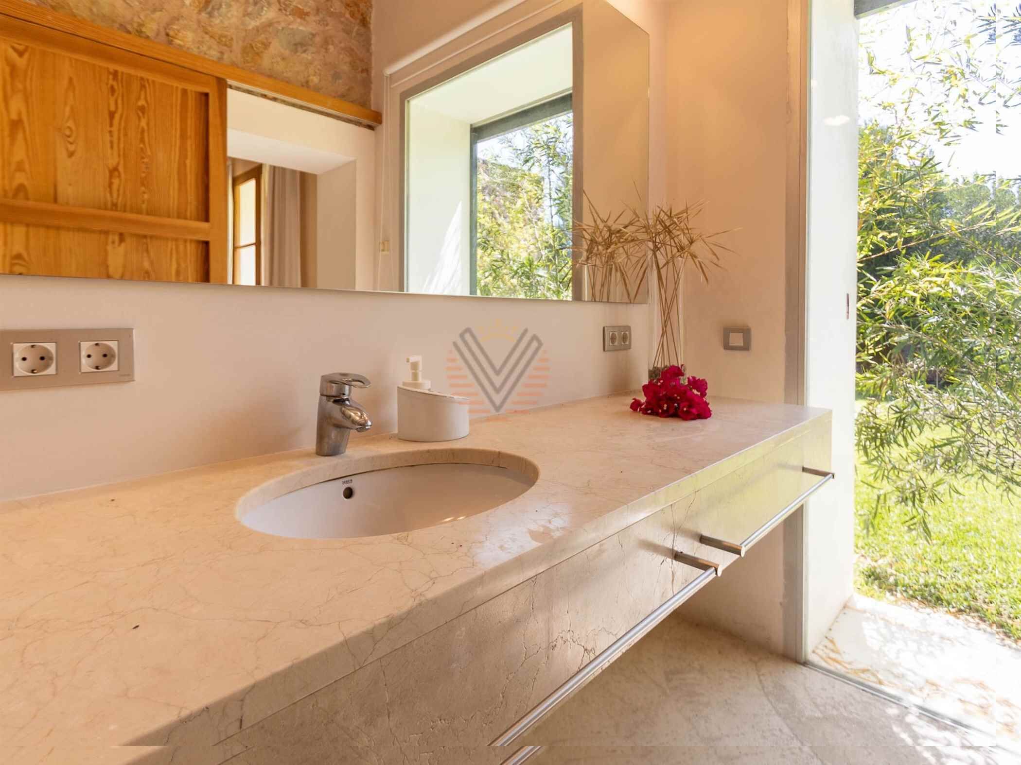 Un baño con un lavamanos grande, un espejo y una ventana.