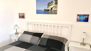 Un lit recouvert d’une couvre-lit à carreaux, deux tables de chevet avec des lampes et deux tableaux encadrés accrochés au mur.