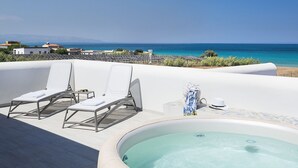 Eine Dachterrasse mit Whirlpool, Liegestühlen und Meerblick.