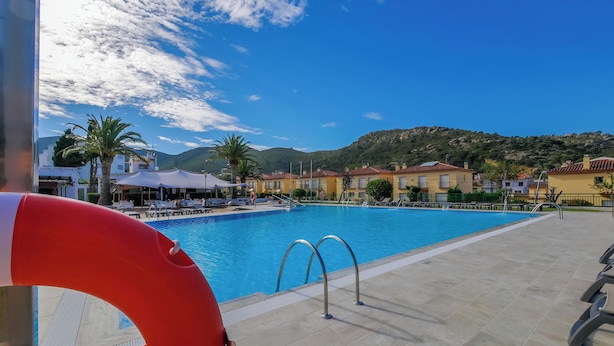 Una piscina con un flotador salvavidas, sillas de descanso y montañas al fondo.
