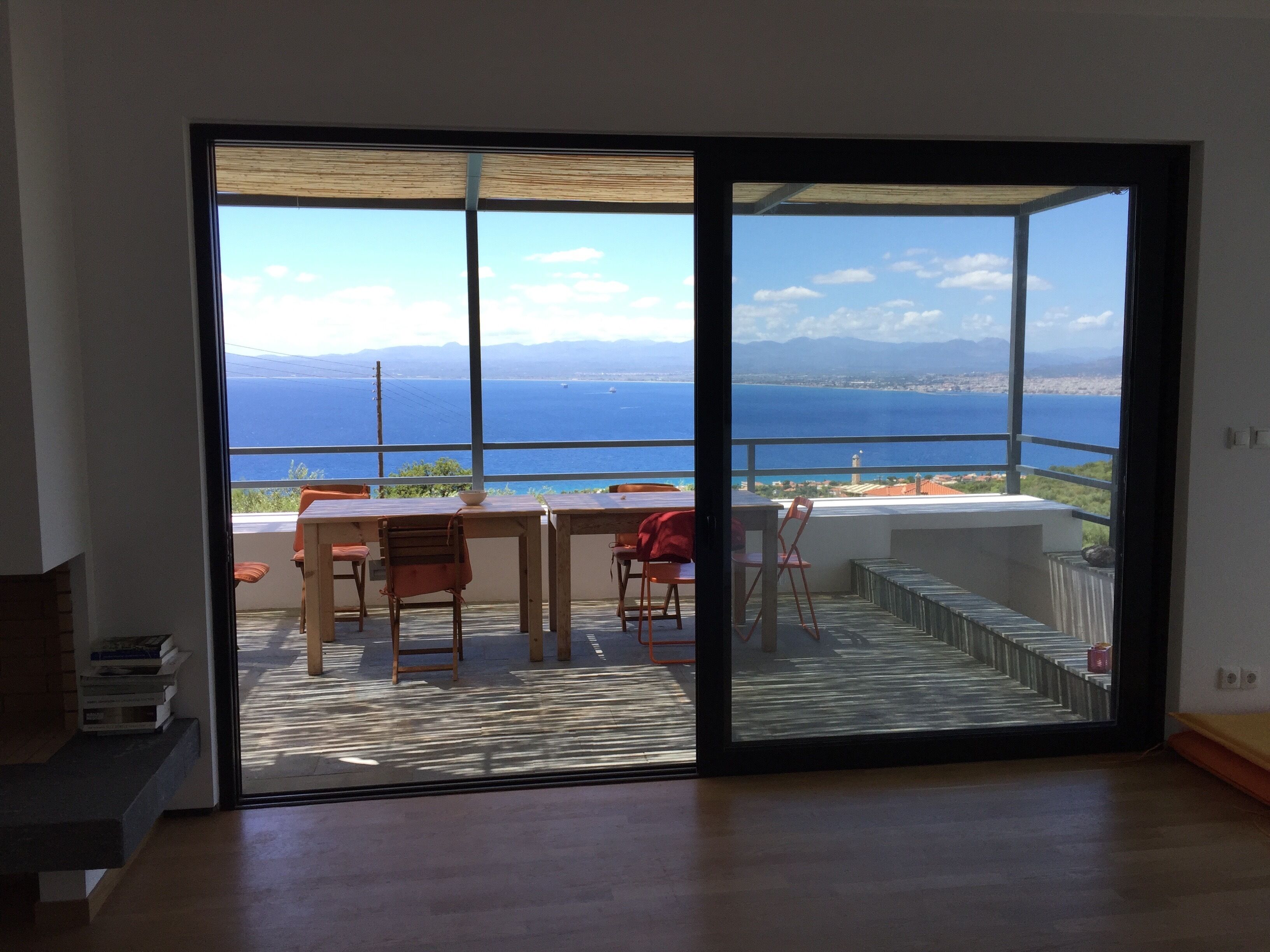 A balcony with a view of the sea, a table, and chairs.