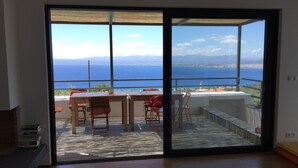 A balcony with a view of the sea, a table, and chairs. - Luxury villa with private heated pool and stunning sea views. (Kalamata)