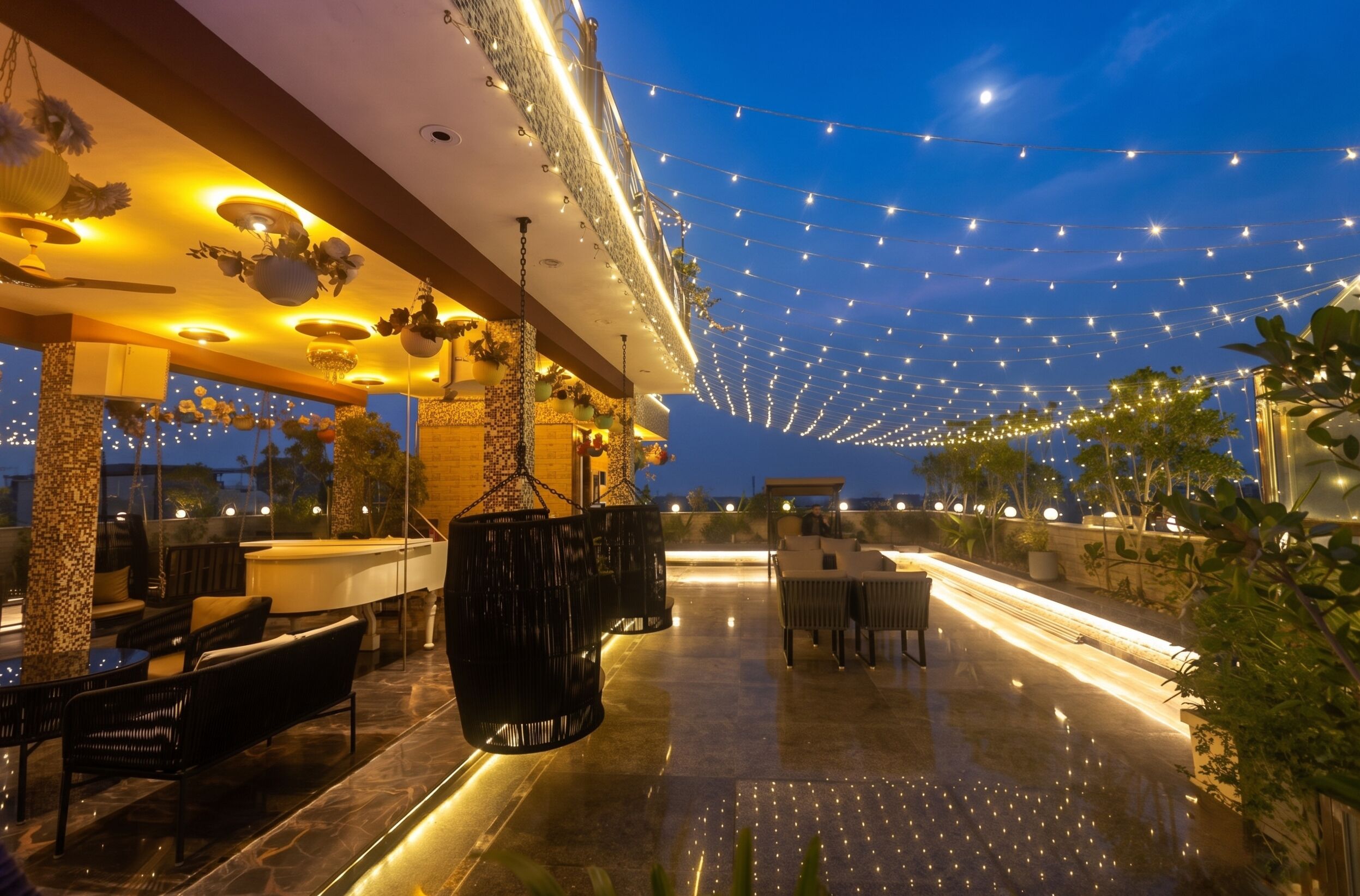 An outdoor lounge area with seating and a pool table, string lights overhead, and a view of the sky.