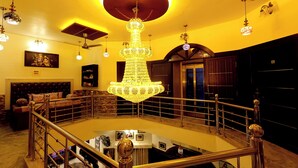 A grand staircase with a chandelier, a seating area with a sofa, and a framed picture on the wall. - Aman Homestay a Boutique Hotel (Agra)