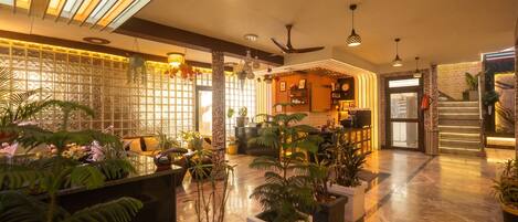 A hotel lobby with a reception desk, seating area, and a staircase.