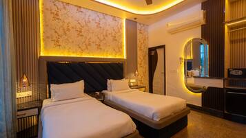 A hotel room with two beds, a ceiling fan, a mirror, and a minibar.