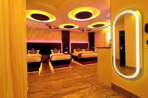 Habitación de hotel con dos camas, un espejo grande y luces de techo circulares.