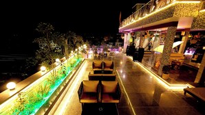 A rooftop terrace with outdoor seating, a water feature, and a bar area. - Aman Homestay a Boutique Hotel (Agra)