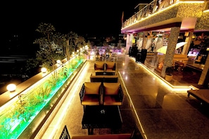 A rooftop terrace with outdoor seating, a water feature, and a bar area. - Aman Homestay a Boutique Hotel (Agra)