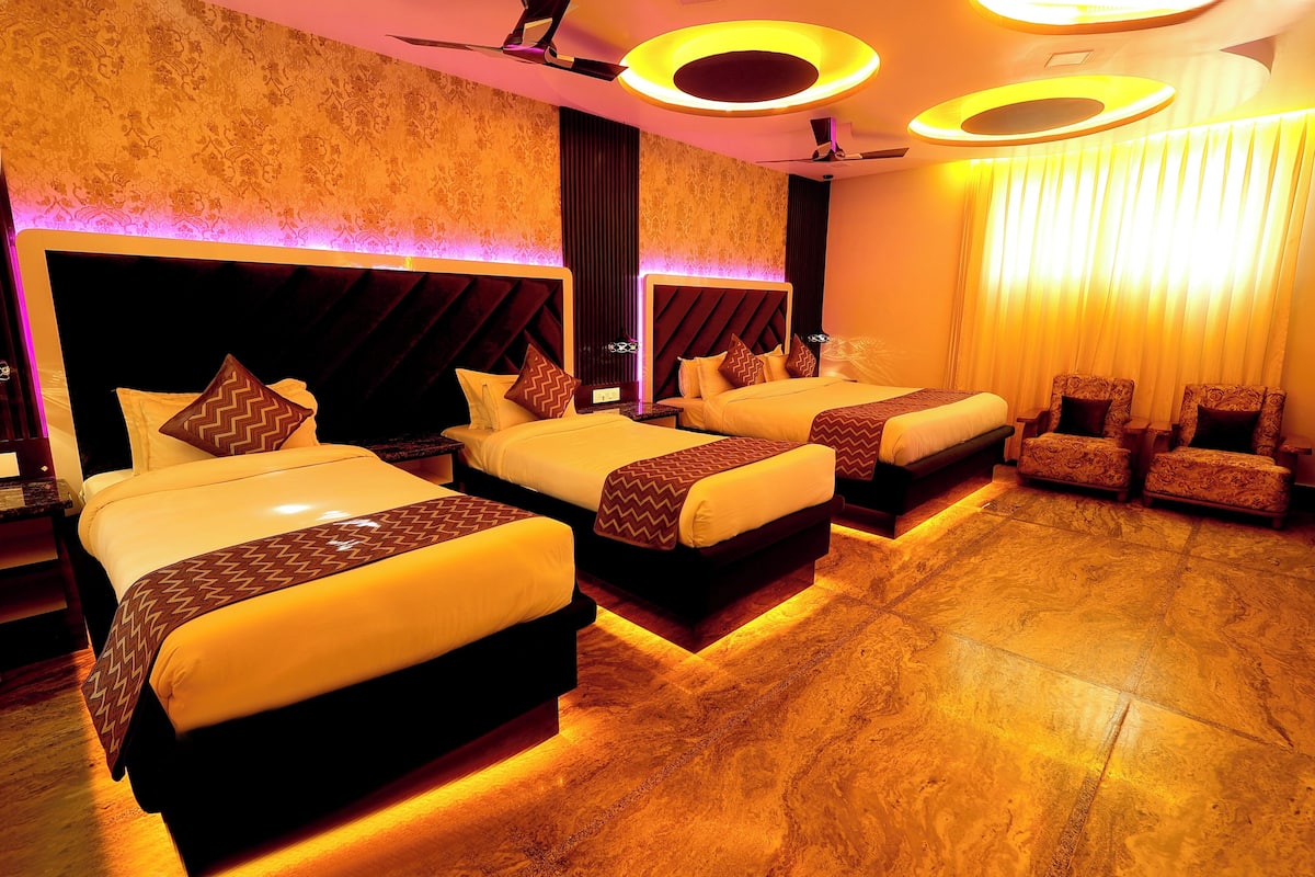 A hotel room with three beds, a seating area, and a patterned wall.