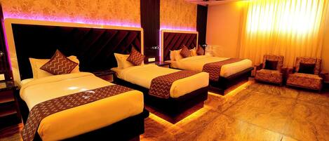 A hotel room with three beds, a seating area, and a patterned wall.
