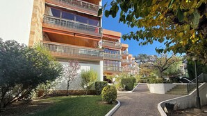 A multi-story residential building with balconies, a paved pathway, and surrounding greenery. - Agi Can Parramon A Apartamento for rent in Roses Girona. (Rosas / Roses)