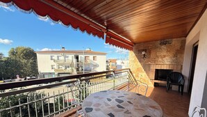 A balcony with a tiled table and chairs, a stone wall, and a view of buildings in the background. - Agi Can Parramon A Apartamento for rent in Roses Girona. (Rosas / Roses)