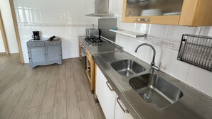 A modern kitchen with stainless steel appliances, a double sink, and wooden cabinets.