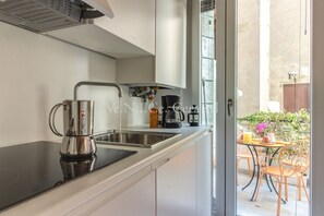 A kitchen with a black countertop, stainless steel sink, and a coffee maker.