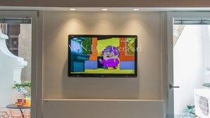 Un téléviseur à écran plat fixé au mur dans une pièce dont le plafond est en bois.