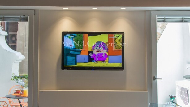 Un téléviseur à écran plat fixé au mur dans une pièce dont le plafond est en bois.