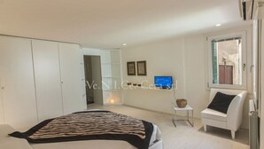 Une chambre à coucher moderne avec un lit, une armoire blanche, une petite table de chevet et une chaise.