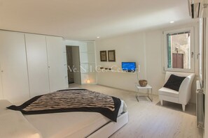 Une chambre à coucher moderne avec un lit, une armoire blanche, une petite table de chevet et une chaise.