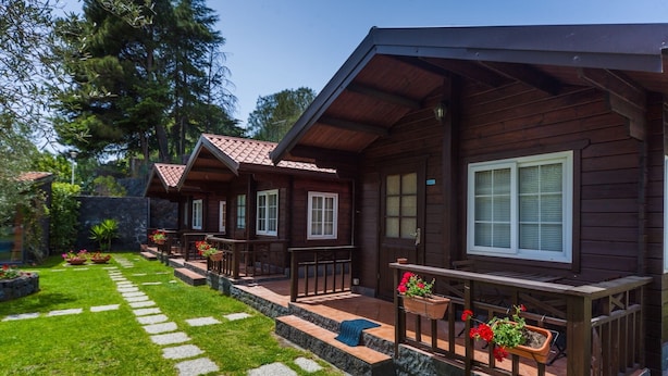 Een rij houten vakantiehuisjes met balkons, stenen trappen en bloempotten.