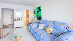 A living room with a blue sofa, a glass coffee table, a white cabinet, and a painting on the wall. - STA. MONICA 3ºA - Apartment for 6 people in Rosas / Roses (Roses)