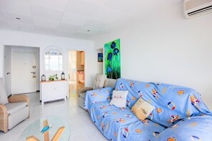 A living room with a blue sofa, a glass coffee table, a white cabinet, and a painting on the wall. - STA. MONICA 3ºA - Apartment for 6 people in Rosas / Roses (Roses)
