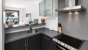 A modern kitchen with a built-in oven, a stainless steel sink, and a view of the sea through a window. - Beachfront two-bedroom apartment with sea views in Canyelles Petites (Roses)