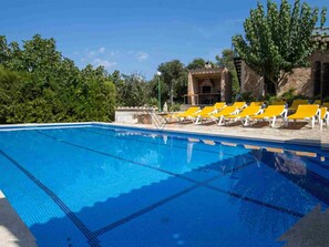 Una piscina blava i cristal·lina amb gandules grogues i un edifici de pedra al fons.