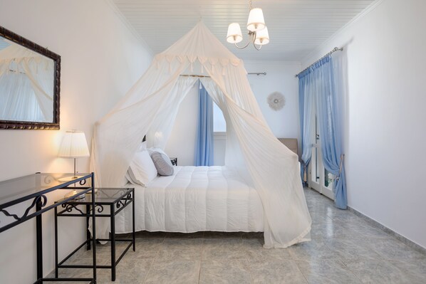 A bedroom with a canopy bed, a bedside table with a lamp, and a mirror on the wall. - Charming Cottage with Private Pool and magnificent sea views! (Zakynthos)