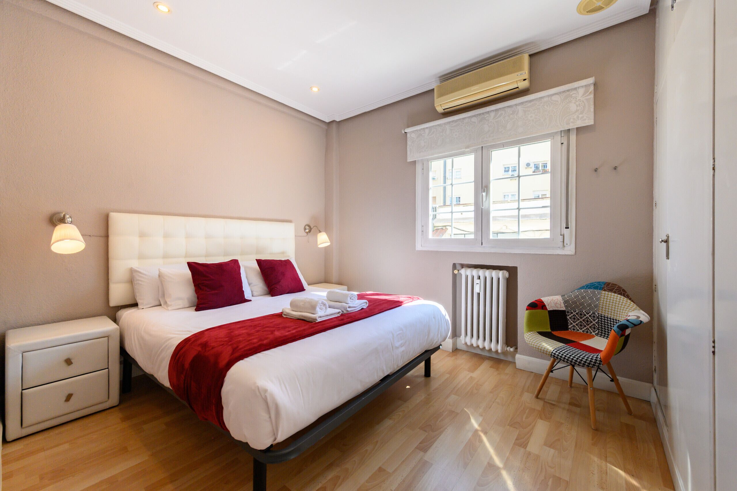 Ein Schlafzimmer mit Bett, Nachttisch, Stuhl, Heizkörper und Fenster.
