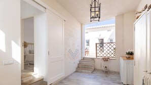 A spacious hallway with a wooden floor, a staircase leading to another room, and a view of the outside. - Ran de Mar, house directly on the beach with spectacular sea views (Alcúdia)