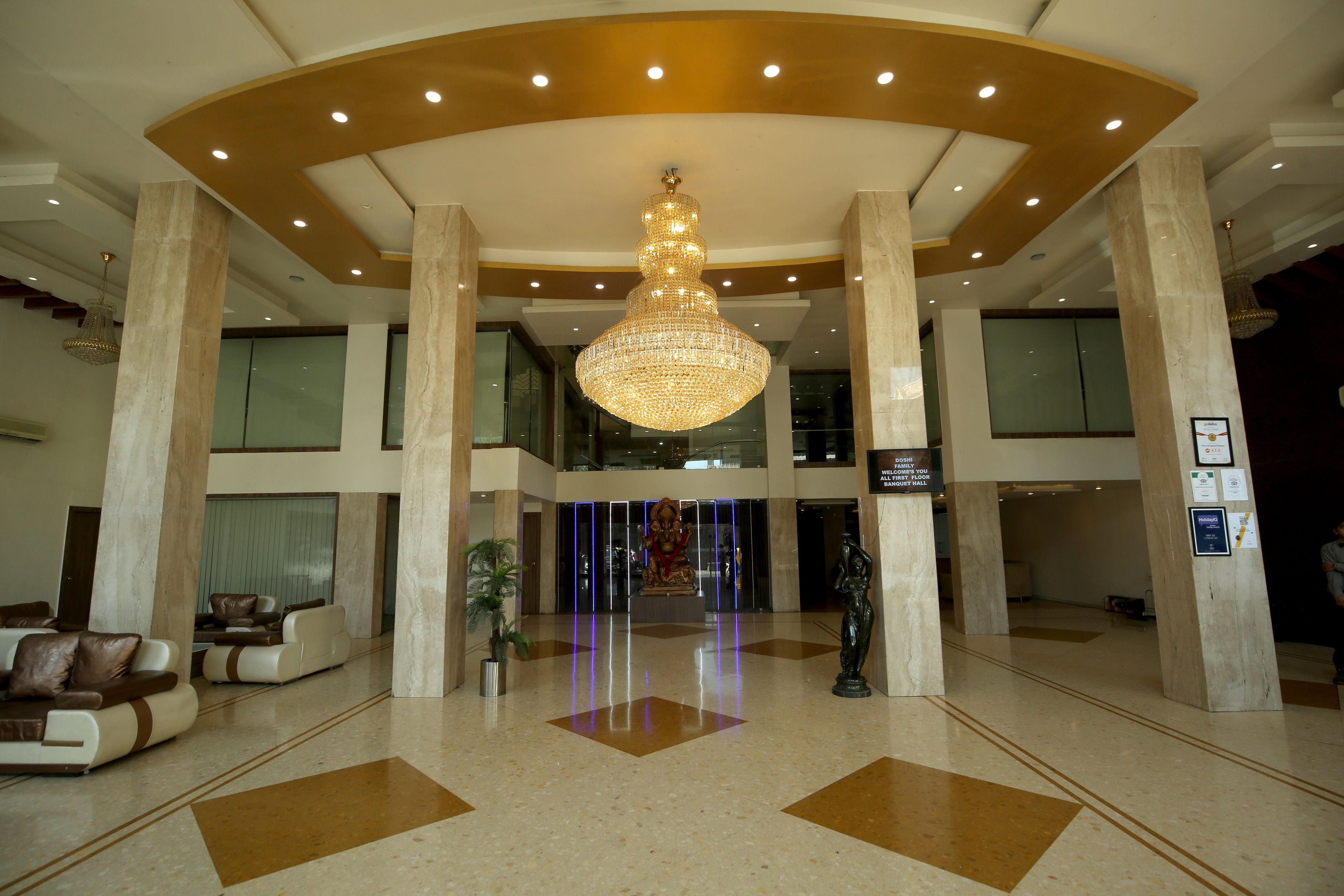 A spacious lobby with a large chandelier, comfortable seating, and a statue.