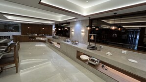 Un lobby moderno de hotel con una larga recepción, área de descanso y un espejo grande que refleja el interior.