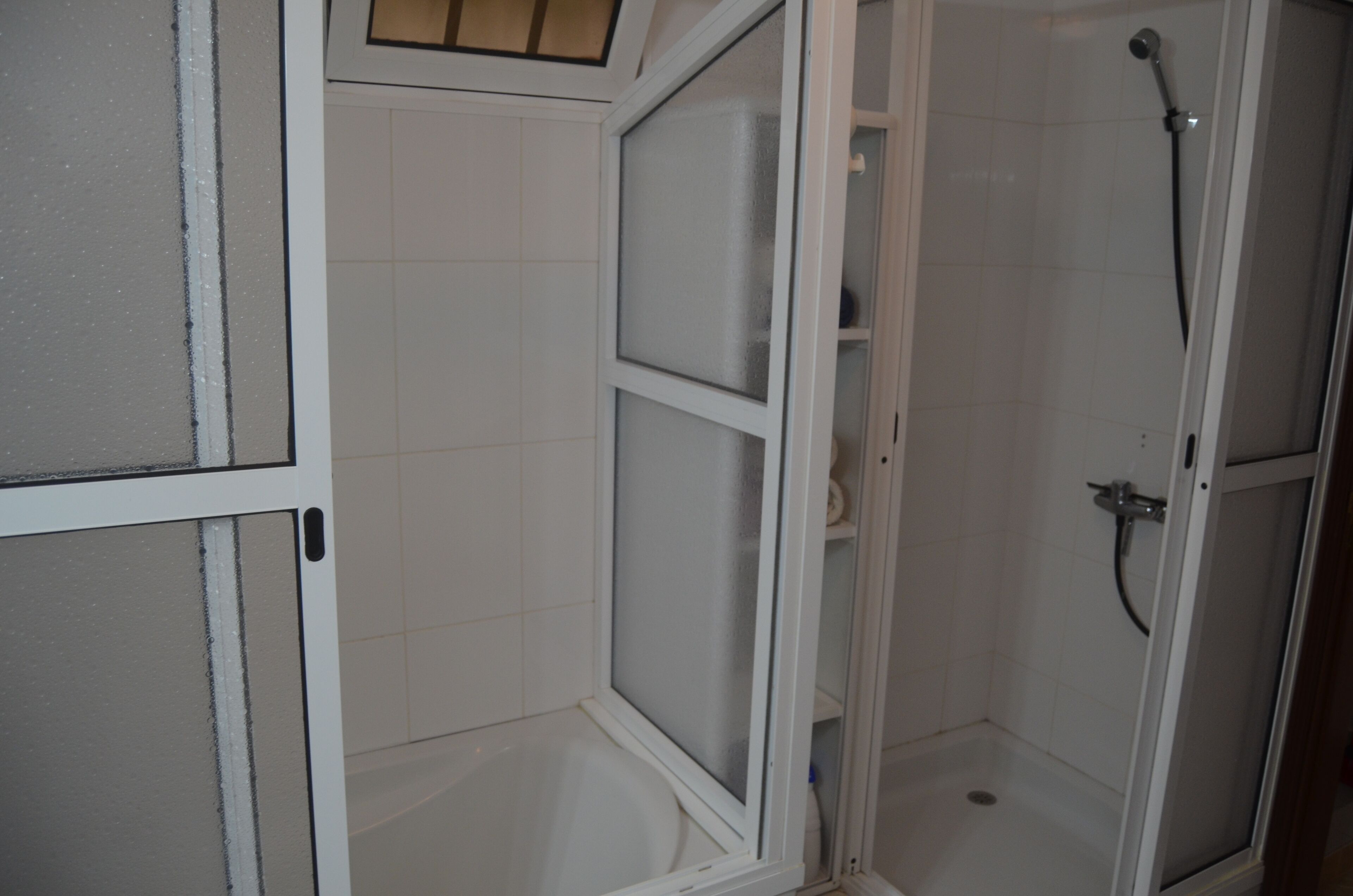 A corner bathroom with a shower, a toilet, and a sink.
