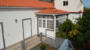 A white building with a red-tiled roof, a small window, and a balcony with railings. - ATLANTIC HOUSE WITH CAR AND BIKE (Câmara de Lobos)