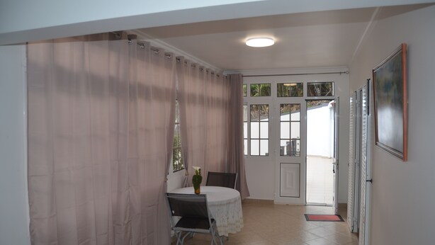 A small dining area with a table and chairs, a door leading outside, and a painting on the wall. - ATLANTIC HOUSE WITH CAR AND BIKE (Câmara de Lobos)