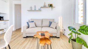 A living room with a sofa, a coffee table, and a plant.