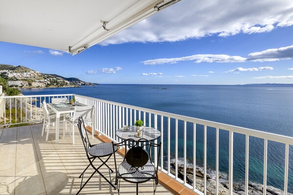 A terrace with a table and chairs overlooking a coastal view.