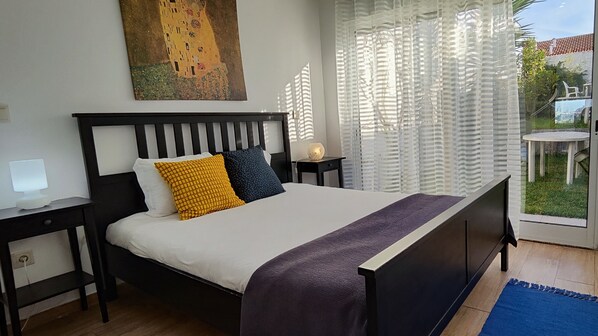 A bedroom with a bed, bedside tables, a lamp, and a painting on the wall.