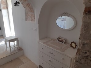 A room with a white dresser, a small table, and a mirror. - Antico Trullo Ulmo - Private pool + Wi-Fi (Ceglie Messapica)