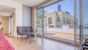 A modern hotel room with a large balcony, a glass table, and a sofa. - P.C. GREGAL 4 ATICO Roses (Rosas / Roses)