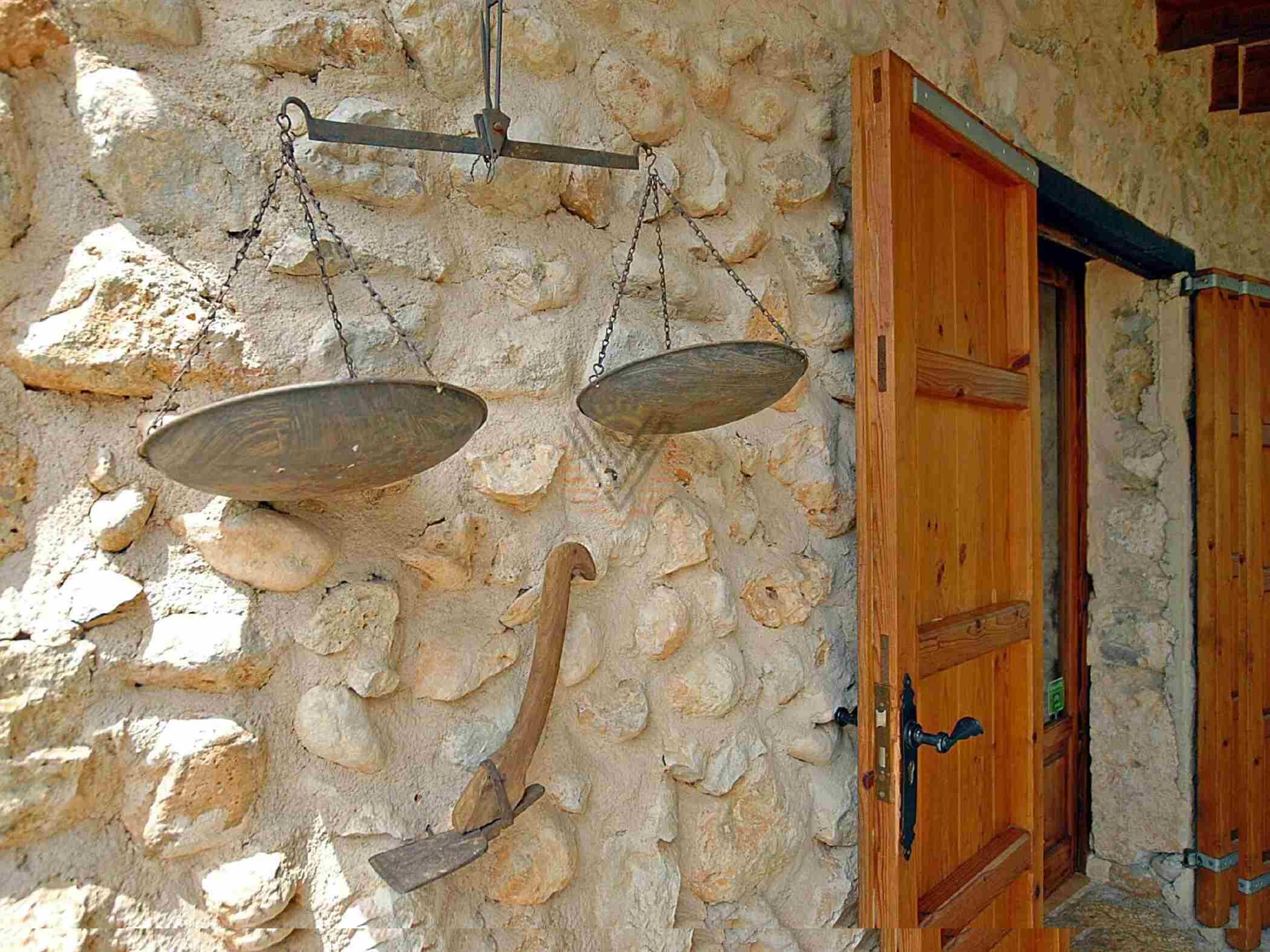 A stone wall with a wooden door and a scale hanging from it.